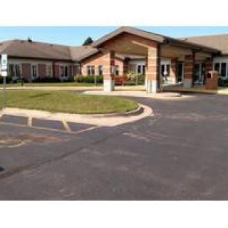 A photo of a building entrance with a parking lot in front.