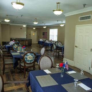 A well-arranged dining room with tables covered in blue tablecloths, decorated with small floral centerpieces.