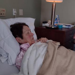 A woman resting in a hospital bed, receiving care.