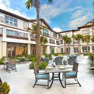 A sunny courtyard with outdoor seating and palm trees.