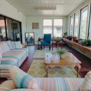 A cozy sunroom featuring striped sofas, a coffee table, and plenty of natural light.