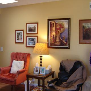 A cozy living room with armchairs, wall art, and a warm lamp.
