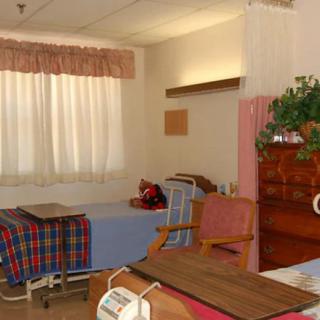 A neatly arranged hospital room with beds and furniture.