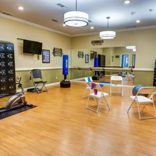 A spacious exercise room equipped with fitness machines, chairs, mirrors, and a television.