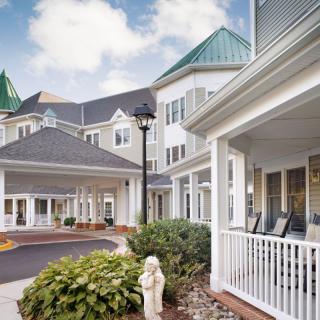 A charming residential building with a porch and lush landscaping.
