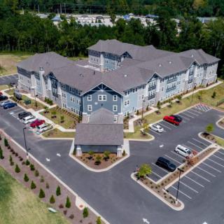 Aerial view of a large residential complex with parking lots and landscaped surroundings.