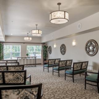 A well-lit interior with arranged seating and decorative elements in a funeral home setting.