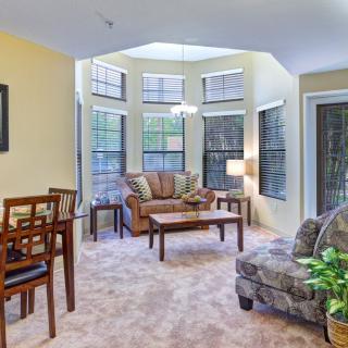 A cozy living room with large windows, sofas, and a dining table.