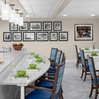 A modern dining area with elegant tables, blue cushioned chairs, and framed pictures on the wall.