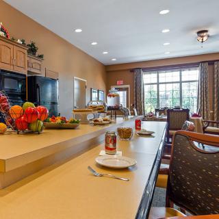 A spacious kitchen and dining area with a long countertop, bar stools, and fruits displayed on the counter.