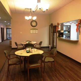 A cozy dining area with a round table and chairs, warm lighting, and simple decor.