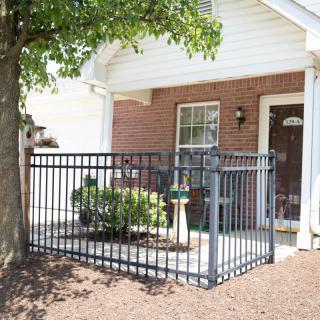 A residential patio with a metal fence and small garden area.