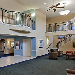 A spacious lobby with modern design, featuring a seating area, stairs, and a ceiling fan.
