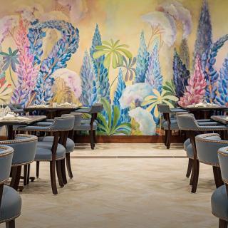 A beautifully decorated restaurant interior featuring a vibrant, colorful mural and elegant dining furniture.