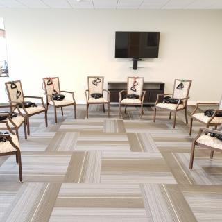 A meeting room with chairs arranged in a circle and a television on the wall.