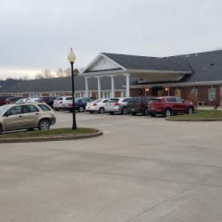 A view of a building with cars parked in front on a cloudy day.