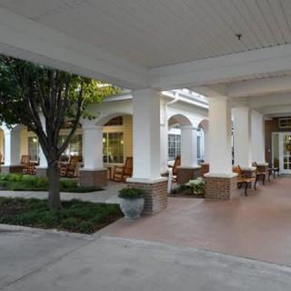 A covered outdoor seating area with columns and landscaping.