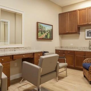 A cozy office or waiting room with chairs, a desk, and cabinets, decorated with artwork on the walls.
