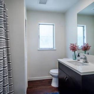 A modern bathroom with a sink, mirror, and toilet, featuring minimal decor.