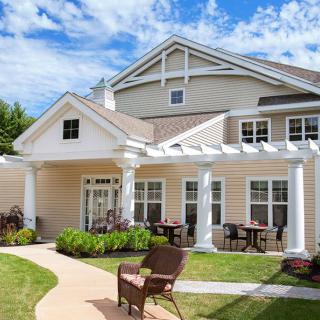 A charming residential house with a large patio and garden area under a clear blue sky.