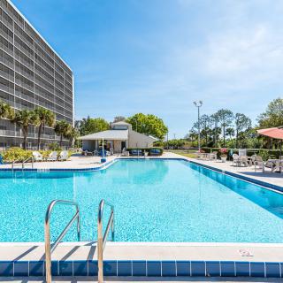 A sunny day at a hotel's outdoor swimming pool with lounge chairs and umbrellas.