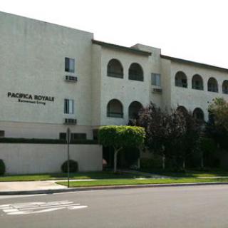 A street view of a multi-story residential building with arched windows and well-maintained landscaping.