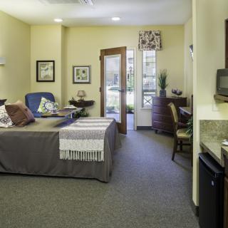 A cozy bedroom with a comfortable bed, desk area, and ample natural light.