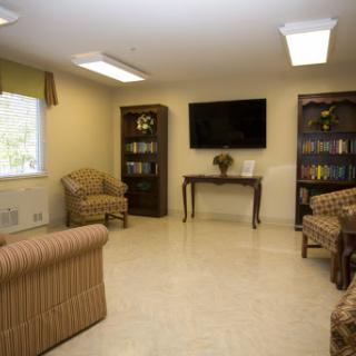 A cozy living room featuring comfortable furniture, a television, and shelves filled with books.