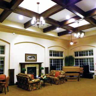 A spacious living room with a coffered ceiling, cozy seating area, and a piano.