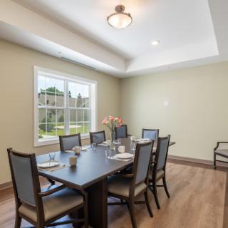 A well-lit modern dining room featuring a wooden table and comfortable chairs.