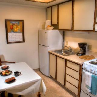 A cozy kitchen with a small dining area, featuring a fridge, stove, and table set for a meal.