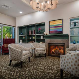 A cozy living room with patterned chairs and a warm fireplace.