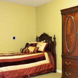 A traditional bedroom with a wooden bed and matching armoire.
