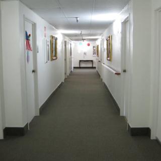 A well-lit hallway with multiple doors and framed pictures on the walls.