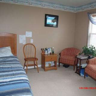 A cozy bedroom with a single bed, two armchairs, and a window allowing natural light.