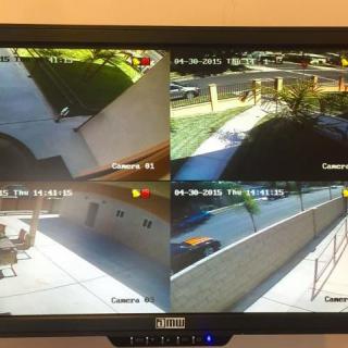 A monitor displaying four CCTV camera feeds of an outdoor area.