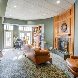A cozy living room with leather furniture, a fireplace, and plenty of natural light.