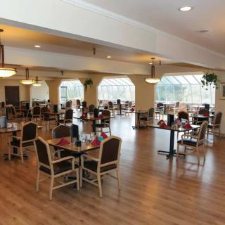 A spacious dining area with neatly arranged tables and chairs, well-lit by large windows.