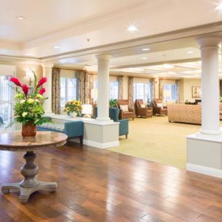 A spacious and elegantly decorated lobby with a seating area, adorned with flowers and featuring hardwood flooring.