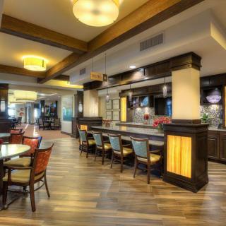 A modern restaurant interior featuring a bar and dining area with stylish furniture and warm lighting.
