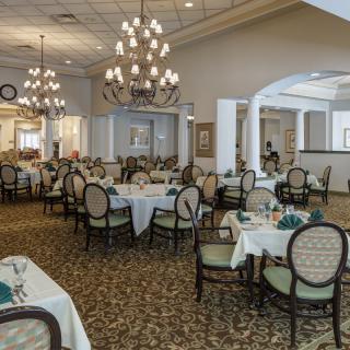 An elegant dining room with neatly arranged tables and chairs, adorned with chandeliers.