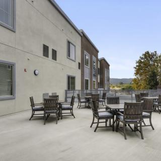 An outdoor patio area with several tables and chairs set against a building backdrop.