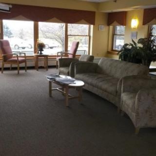 A cozy living room with a sofa, chairs, and large windows allowing natural light.
