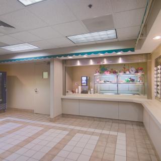 Empty interior of a commercial waiting area with a reception desk and tile flooring.