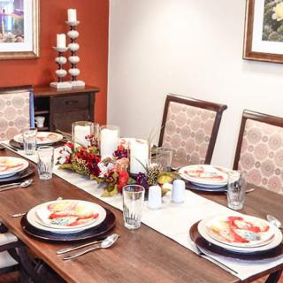 A well-decorated dining table with elegant place settings, featuring candles and a floral centerpiece.