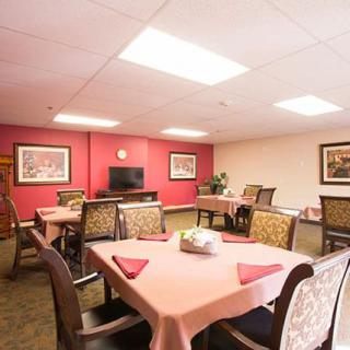 A well-lit dining area with neatly arranged tables and chairs, adorned with decorative paintings.
