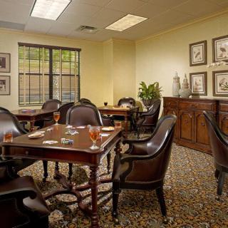 A well-furnished conference room with wooden tables and leather chairs, set up for a formal meeting.