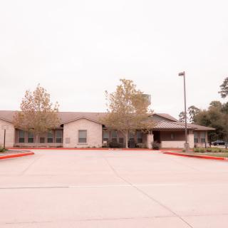 A suburban building with a parking lot on an overcast day.