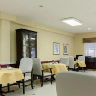 A well-arranged dining area with several tables and chairs, featuring a decorative cabinet and window blinds.