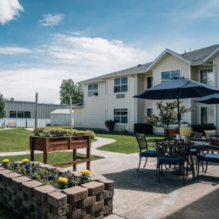 A sunny day in a courtyard featuring patio furniture and a garden area.